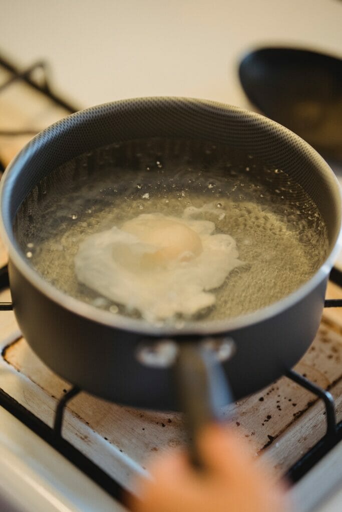 open egg simmering in water cooking methods